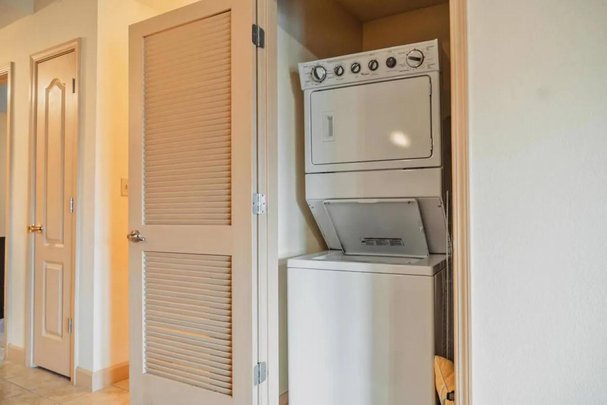 A practical laundry area featuring a modern washer-dryer unit neatly tucked behind closed doors. The design is efficient and ensures guests have easy access to laundry facilities without sacrificing space.