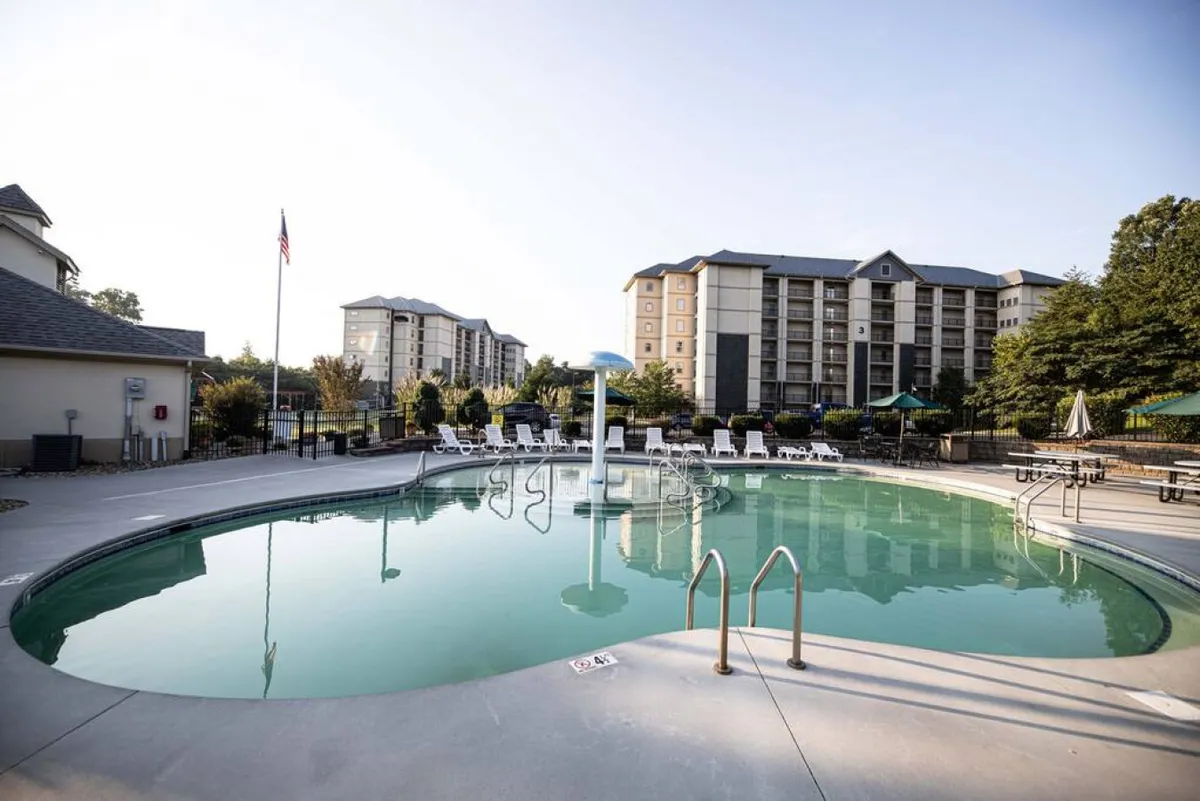 This exterior image showcases the property's swimming pool area surrounded by lounge chairs, lush greenery, and the building facade in the background. The environment is relaxed and inviting, ideal for both socializing and quiet enjoyment.