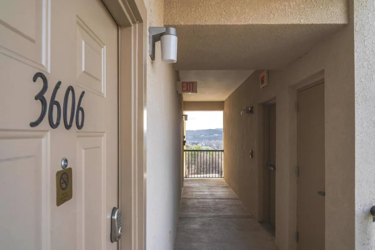 A welcoming view of the entryway to Unit 3606 with the unit door, exit sign, and balcony, suggesting accessibility and community. The balcony view implies scenic surroundings and easy access for all guests.