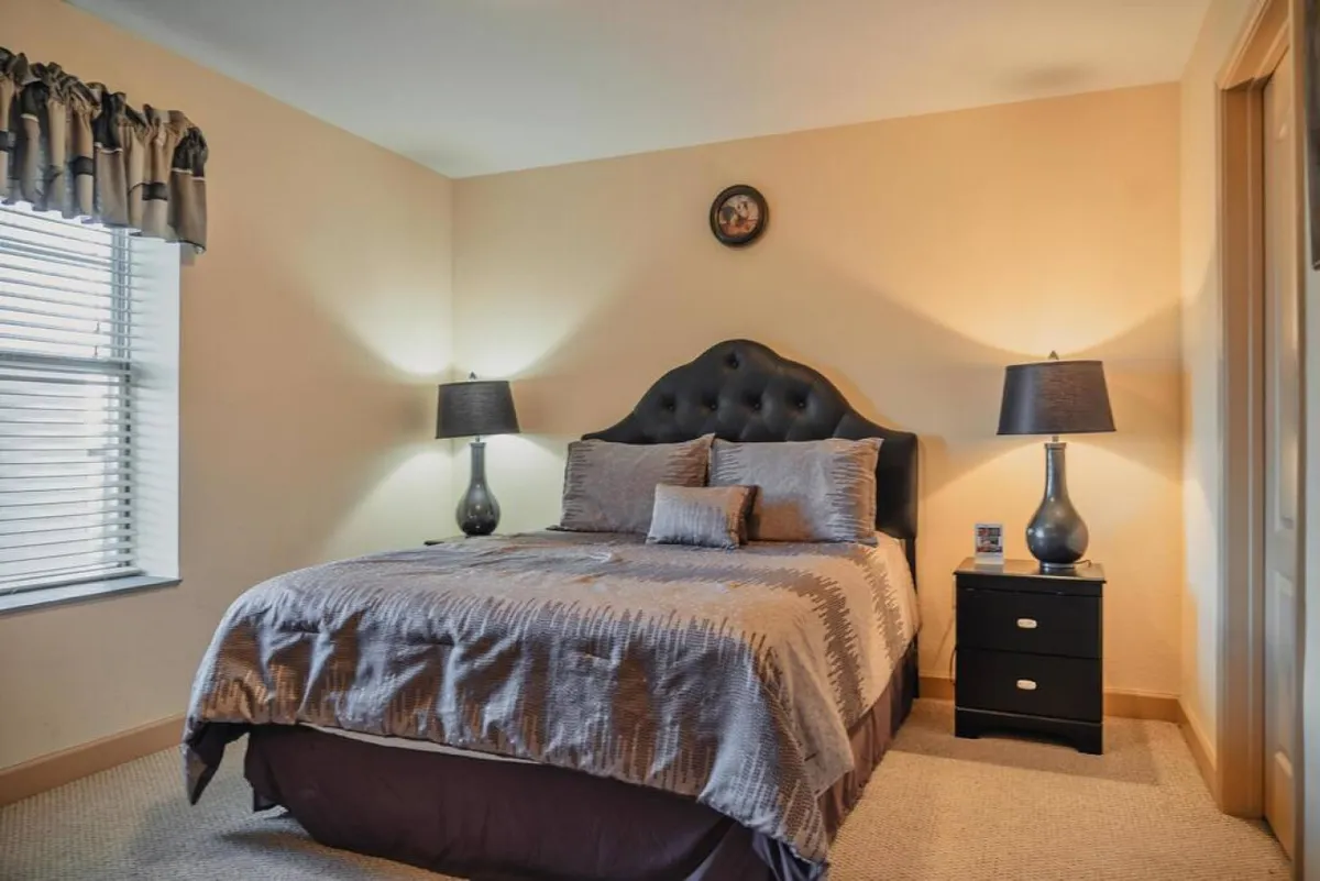 A tranquil bedroom with a comfortable bed, matching nightstands and lamps, and a bright window that lets in natural light. The overall vibe is cozy and peaceful, reinforcing the idea of a private sanctuary.