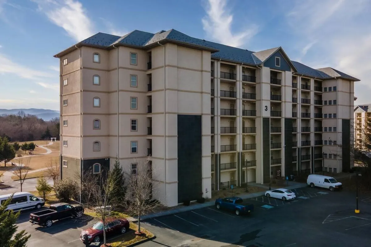 This image shows the exterior of the building, including the parking area and surrounding landscape. The tranquil mood and vantage point hint at the property's central location and provide a sense of arrival and connection to the broader neighborhood.