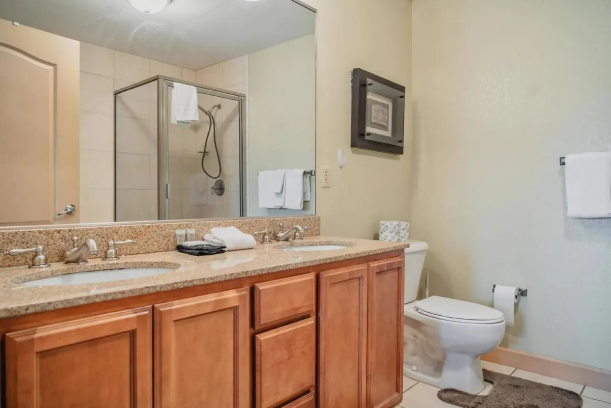 A modern, inviting bathroom showcasing a double sink vanity, a glass shower enclosure, and a large framed mirror. The space is bright, organized, and perfect for self-care routines and relaxing after a busy day.